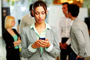 Portrait of a beautiful businesswoman using smartphone in front of colleagues