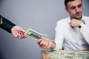 Unhappy man giving money to woman