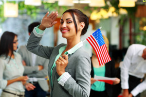 Patriotic businesswoman standing with USA flag in front of colleagues