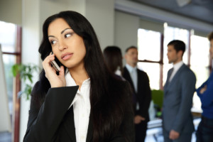 Beautiful businesswoman talking on the phone with colleagues on background