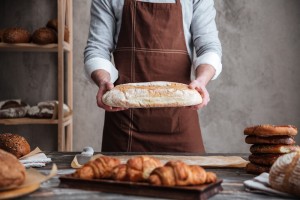 Man baker holding bread - Bakery Business Plan