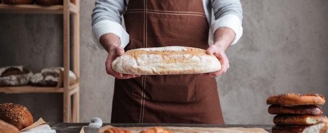 Man baker holding bread - Bakery Business Plan