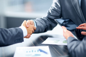 Business men shaking hands over papers